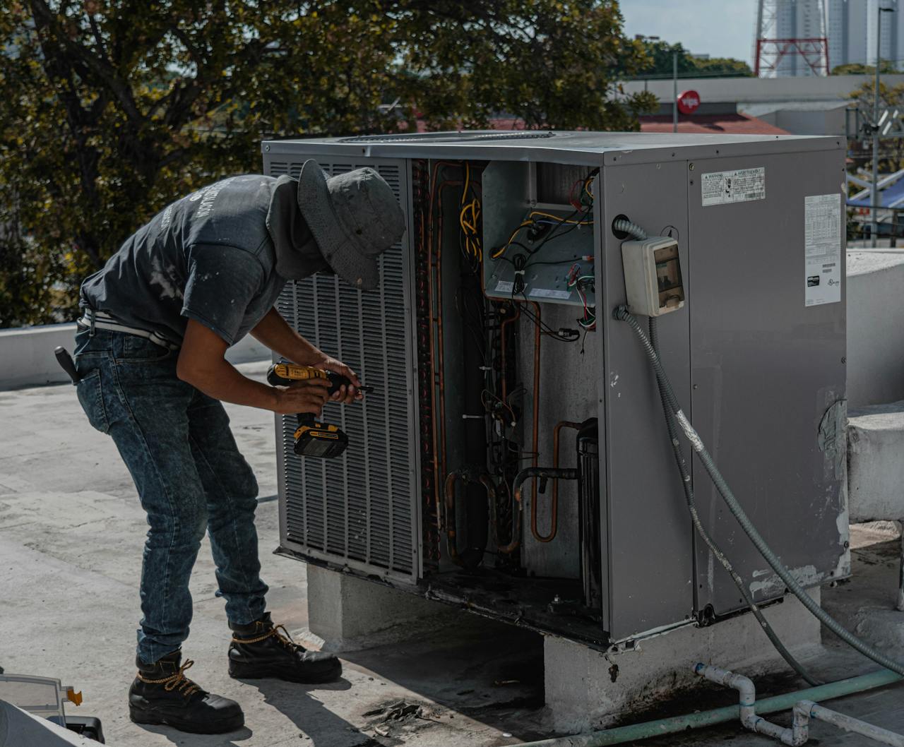 stats-img A worker in a bucket hat repairs an outdoor air conditioning unit on a rooftop.